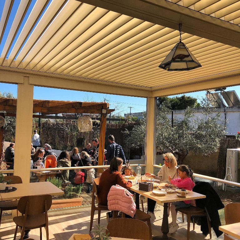 tourists eating at 'The Orchard in Vari' terrace in the shade of the wooden beams